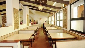A restaurant with high ceilings, patterned wall decorations, and a long counter with seating. - Hotel Panchavati Yatri (Nashik)