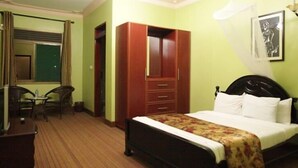 A hotel room with a bed, a wardrobe, a desk, and a chair.
