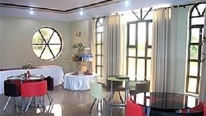 A hotel dining area with round tables, chairs, and a large window with curtains.