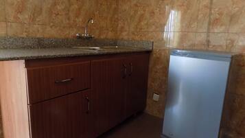 A kitchen with a sink, cabinets, and a refrigerator.