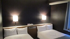 Ein Hotelzimmer mit zwei Betten, einer Bedienkonsole und zwei Wandlampen.