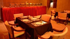 Un salón de conferencias con una larga mesa preparada para una reunión, rodeado de sillas.