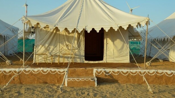 Una carpa con escenario y zona de asientos, rodeada de otras carpas.