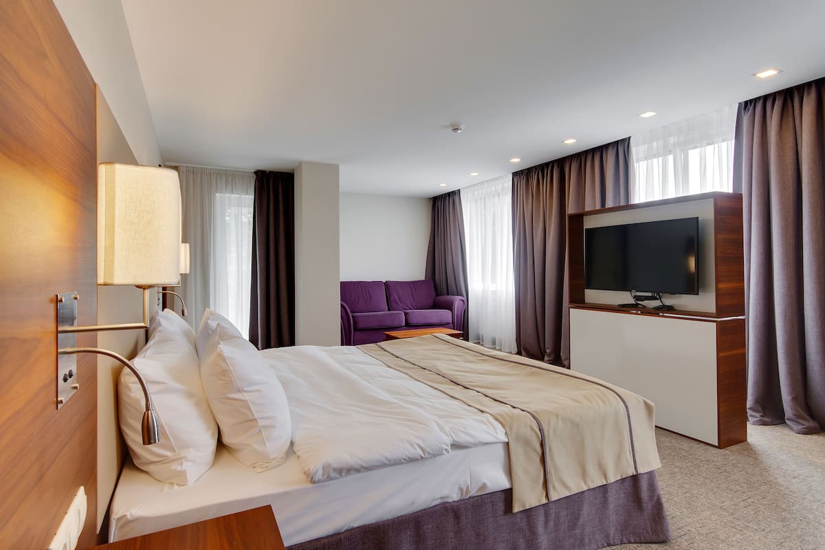 A hotel room with a bed, a TV, a sofa, and a desk.