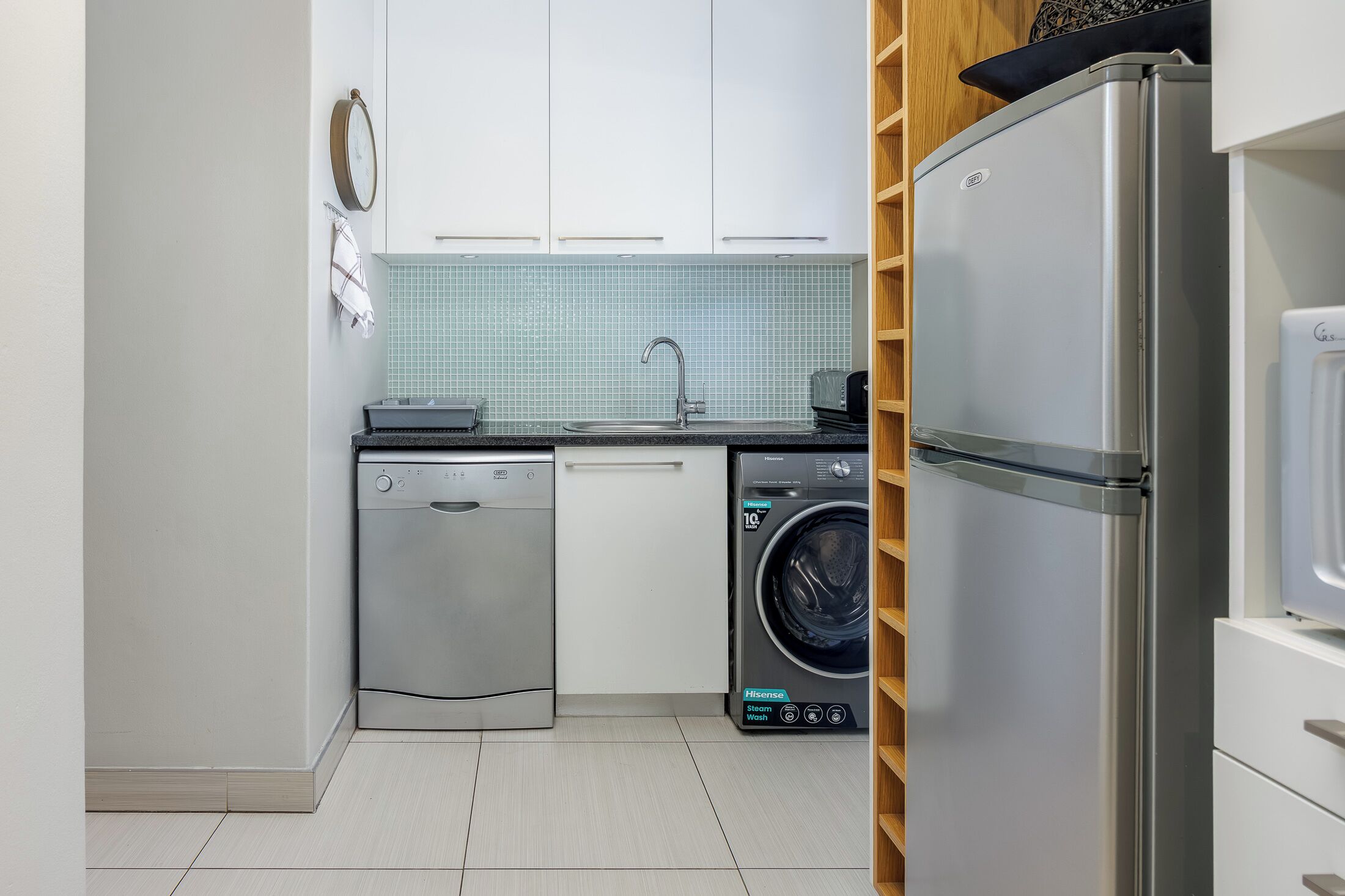 Uma cozinha compacta com máquina de lavar louça, máquina de lavar roupa e frigorífico.