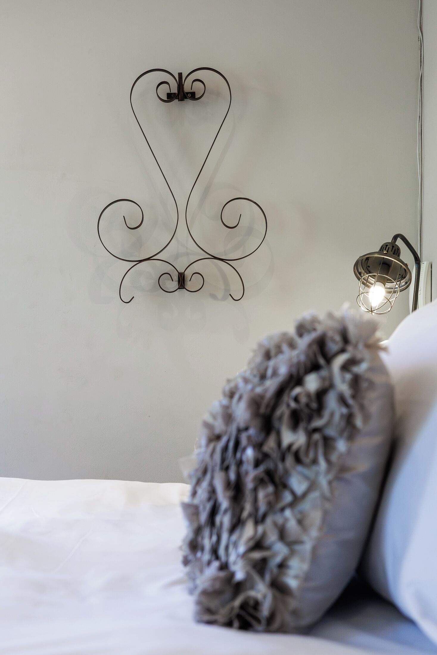 Een slaapkamer met een decoratief wandobject en een bedlamp.