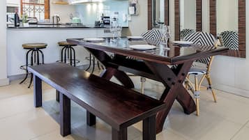 Uma cozinha moderna com área de jantar, apresentando uma mesa e cadeiras de madeira, um banco e uma ilha central com banquetas.