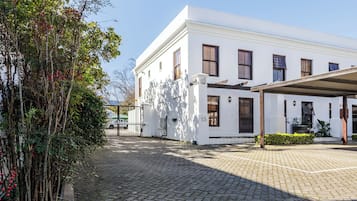 Un bâtiment blanc doté d’une cour pavée, d’un espace extérieur couvert aménagé en coin salon et du chiffre « 15 » apposé sur la façade.