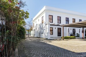 Un edificio blanco con un patio empedrado, un espacio de estar techado al aire libre y el número 15 en el edificio.