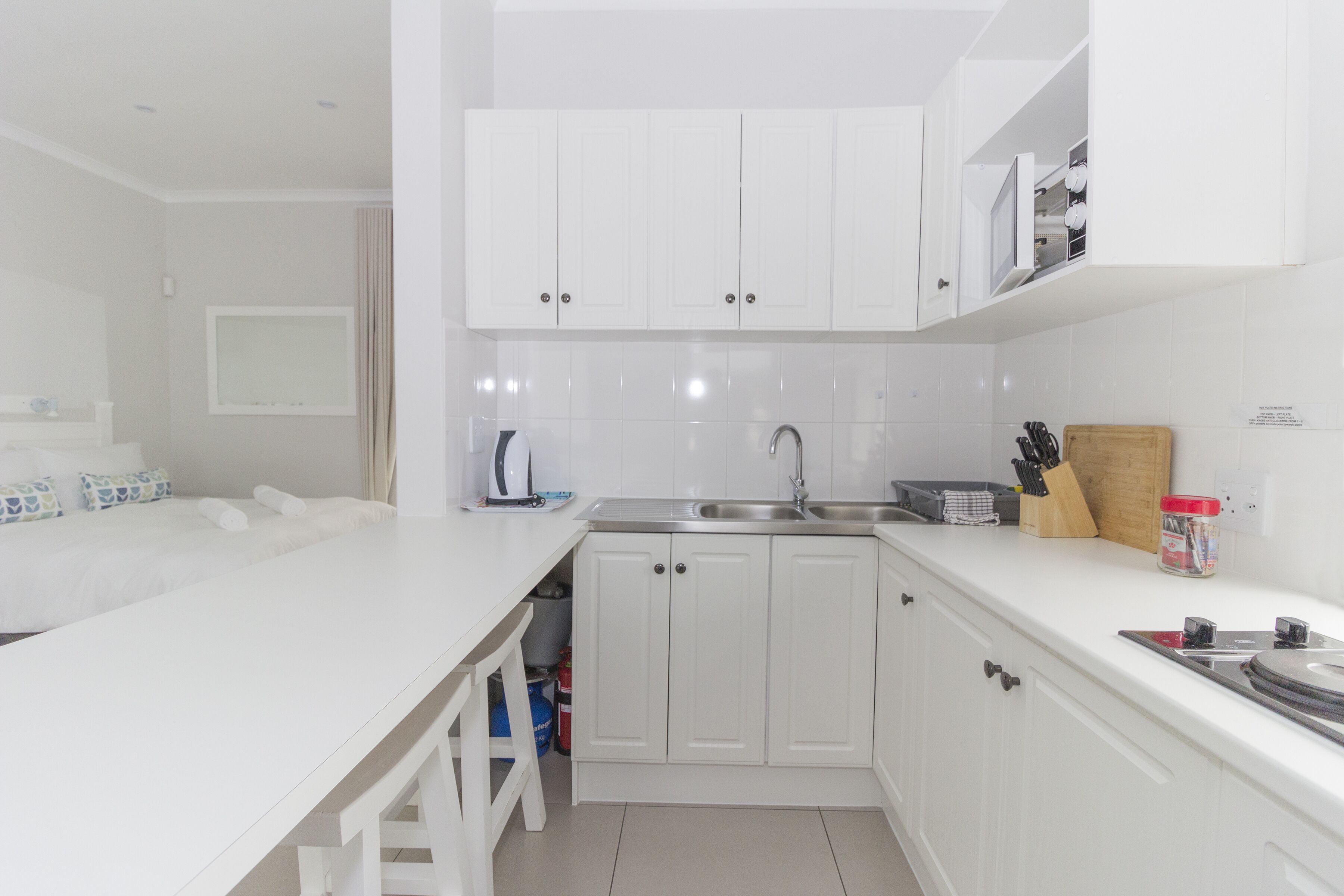 Una cocina moderna con armarios blancos, un lavamanos integrado y una encimera con tabla de cortar y utensilios.