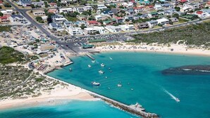 An aerial view of a coastal town with a beach, boats, and a pier.
