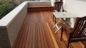 A wooden deck with a table and chairs, overlooking a residential area.