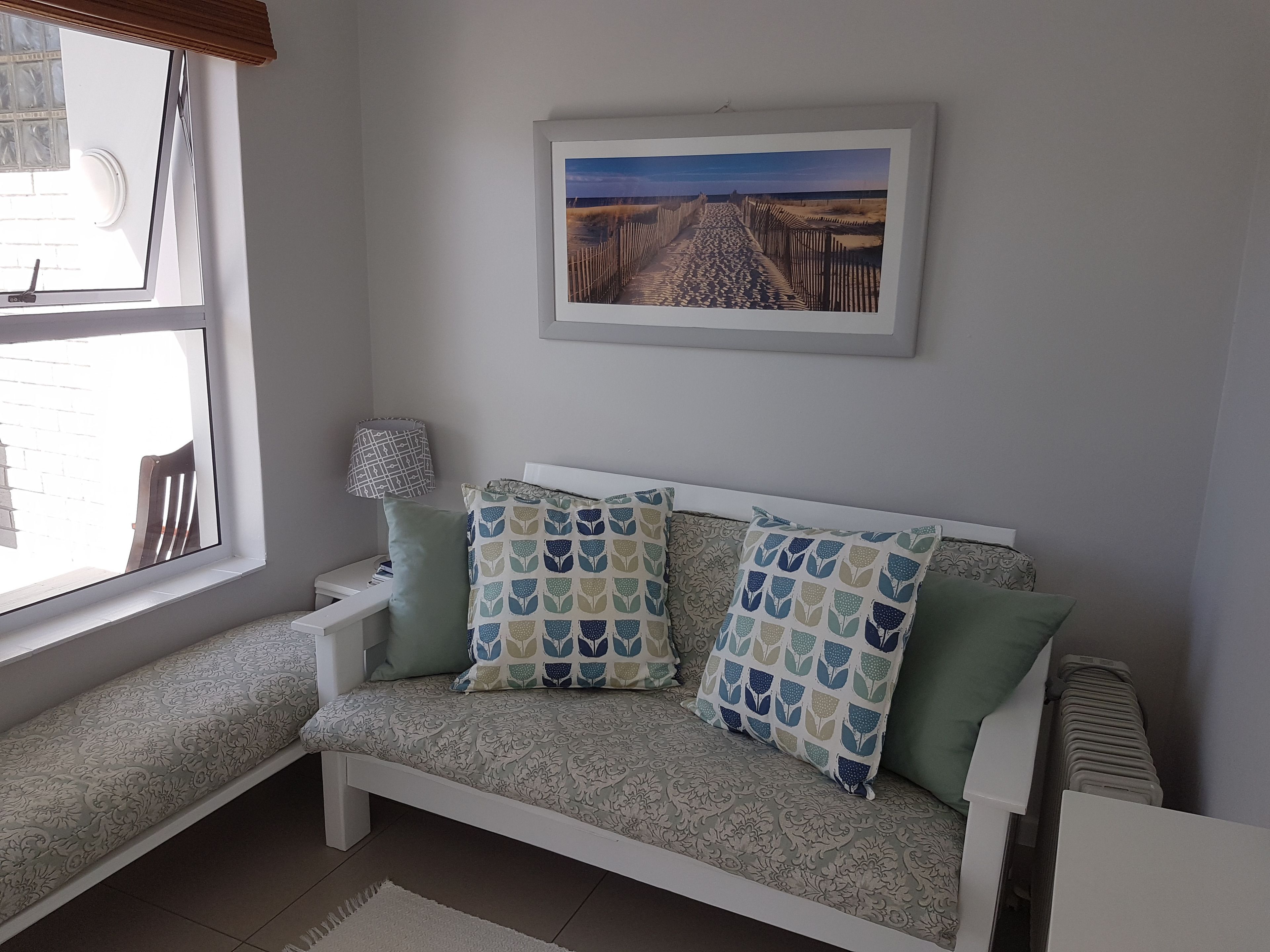 A cozy room with a bench, a framed picture on the wall, and a window with blinds.