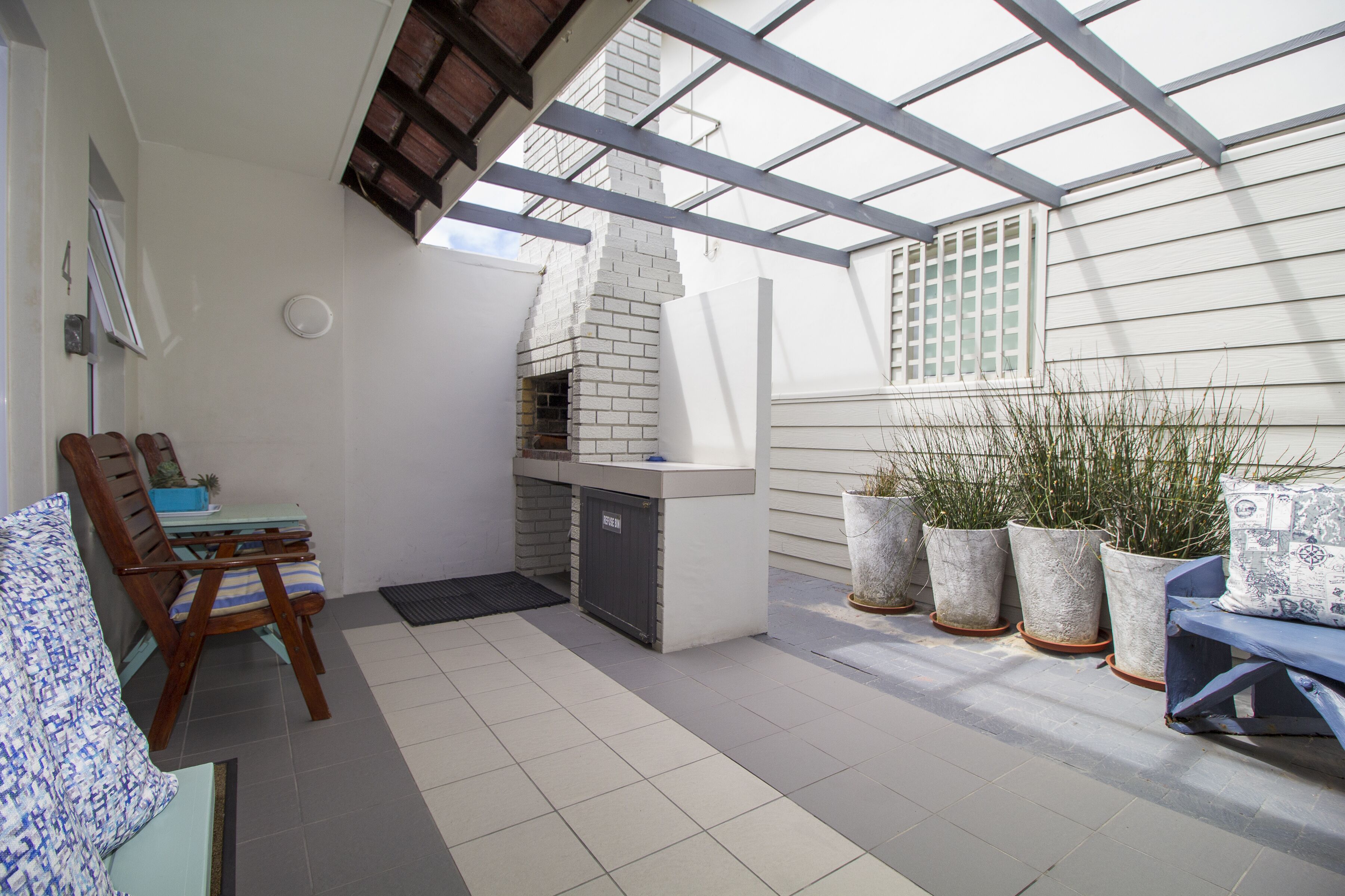 A covered patio with a brick fireplace, outdoor seating, and potted plants.