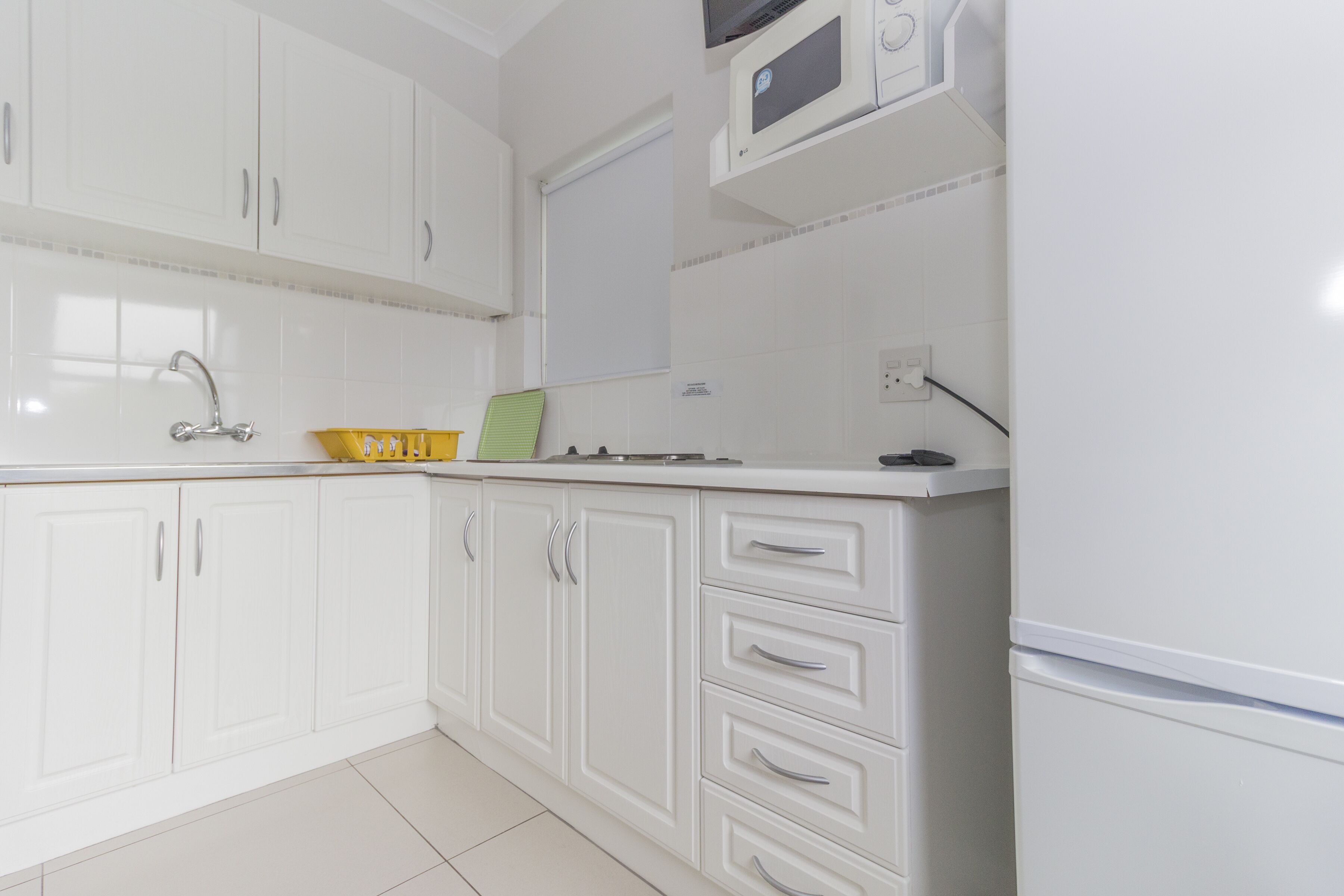 A kitchen with white cabinets, a microwave, and a sink.