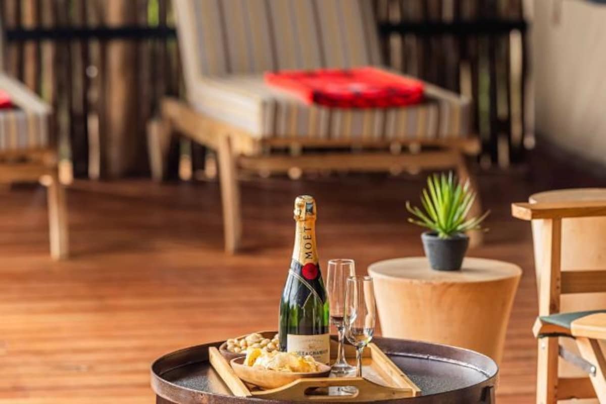 Un rincón de descanso con una mesa de madera, una botella de champán Moët, dos copas y una bandeja con aperitivos.