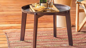Una mesa de madera con una botella de champán, copas y aperitivos en una bandeja.