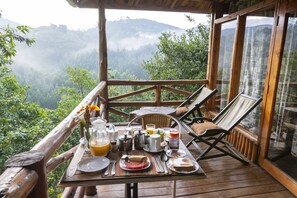 A wooden deck with a breakfast setup overlooking a mountainous landscape. - Rushaga Gorilla Lodge (Bugambira)