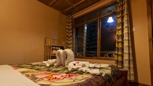 Une chambre d’hôtel avec un lit, une fenêtre avec des rideaux et une tête de lit en bois.