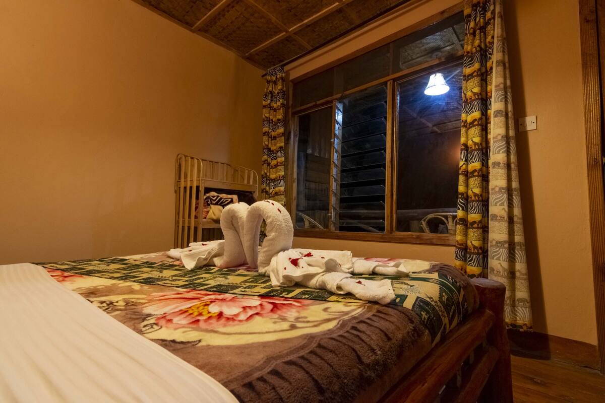 A hotel room with a bed, a window with curtains, and a wooden headboard.