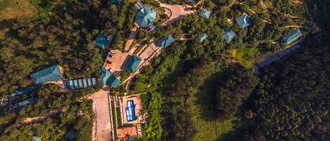 An aerial view of a resort with multiple buildings, a central pool area, and surrounding greenery.