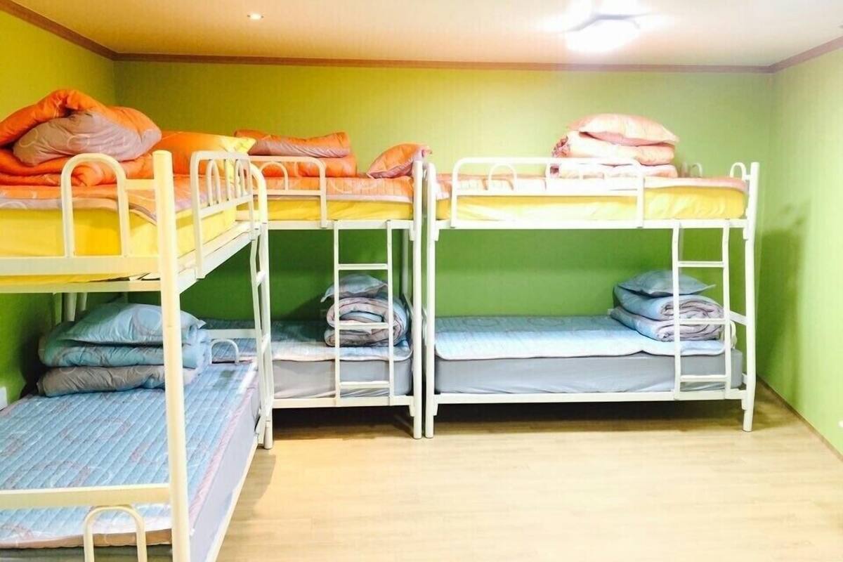 Ein Zimmer mit drei Etagenbetten, jeweils mit Kissen und Decken.