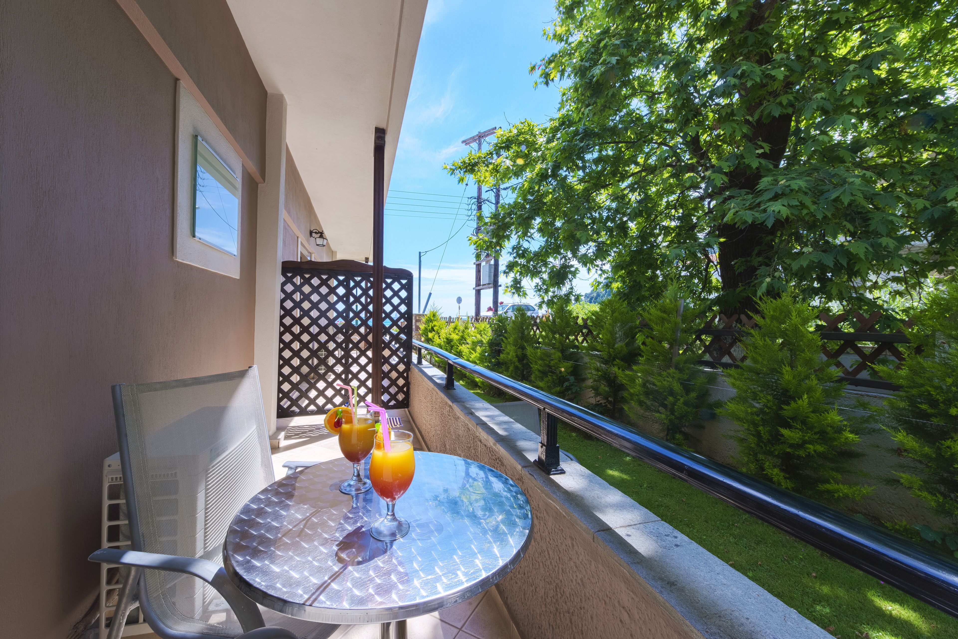 A balcony with a table, two chairs, and two drinks.