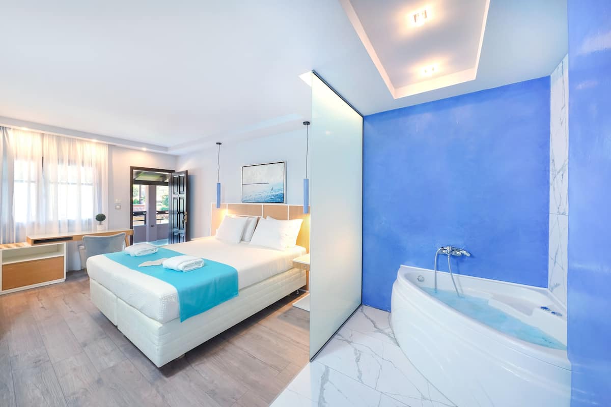 Una habitación de hotel moderna con una cama grande, un baño independiente con bañera y una zona de escritorio.