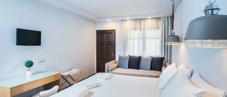 A hotel room with a bed, a desk, a chair, a television, and a window with curtains.