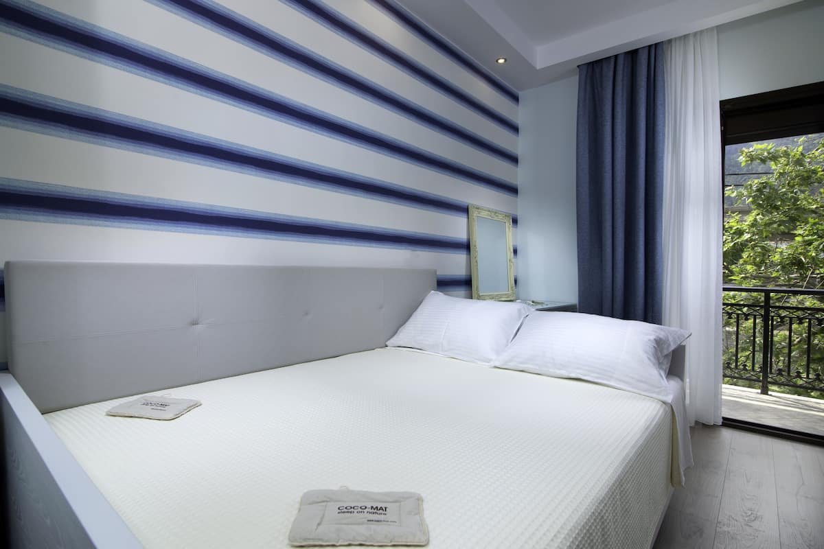 Habitación de hotel con cama, ventana y vista a zonas verdes, y diseño de pared a rayas.