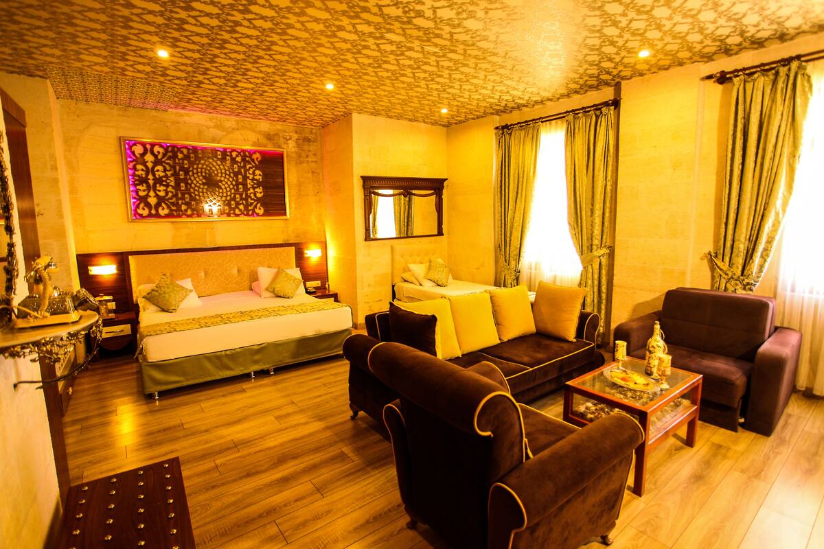 A hotel room with a bed, a sofa, a coffee table, and a chair.