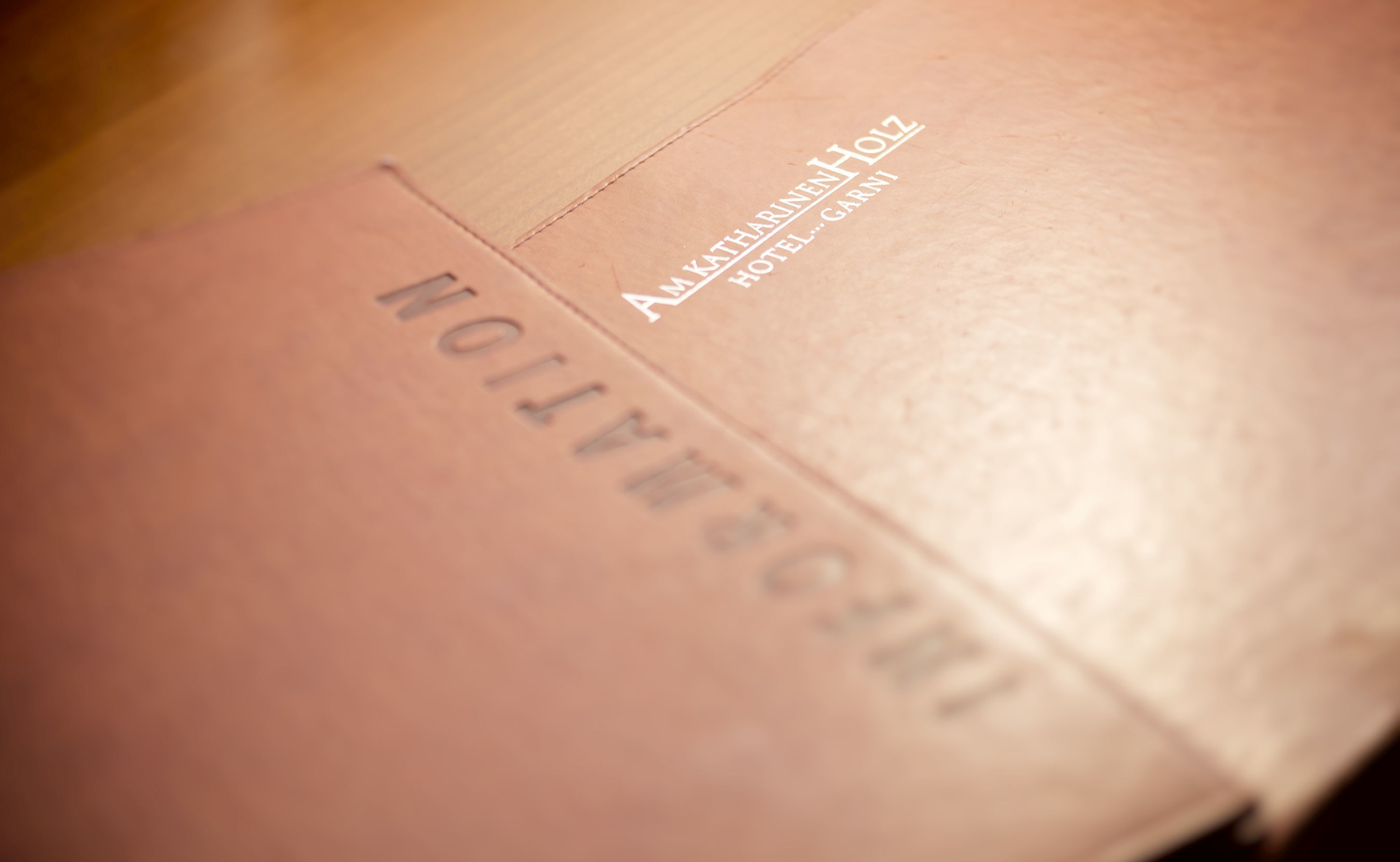 Un libro de tapa de cuero marrón con texto en relieve, probablemente un diario o planificador, con las palabras visibles "KATHARINEN" y "HOTEL...GARNI".