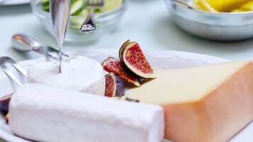 A plate with a large piece of cheese, a wedge of white cheese, and sliced figs.