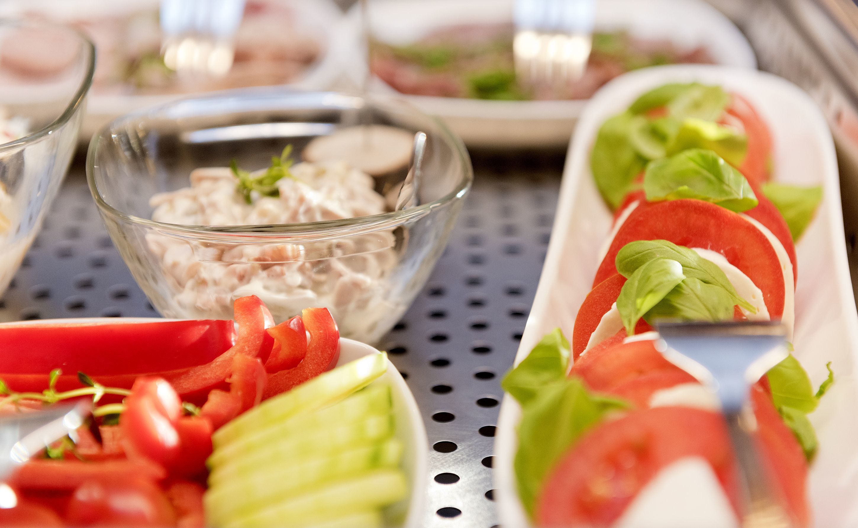 A buffet with various dishes including sliced tomatoes, cucumbers, and a bowl of salad.
