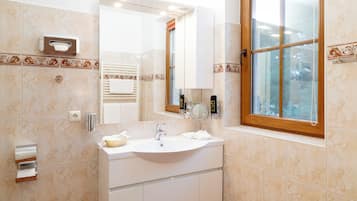 Un baño con lavamanos, espejo, toallero y ventana.
