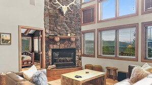 A cozy living room with a stone fireplace, leather sofas, and large windows. - Above the Fray (Breckenridge)