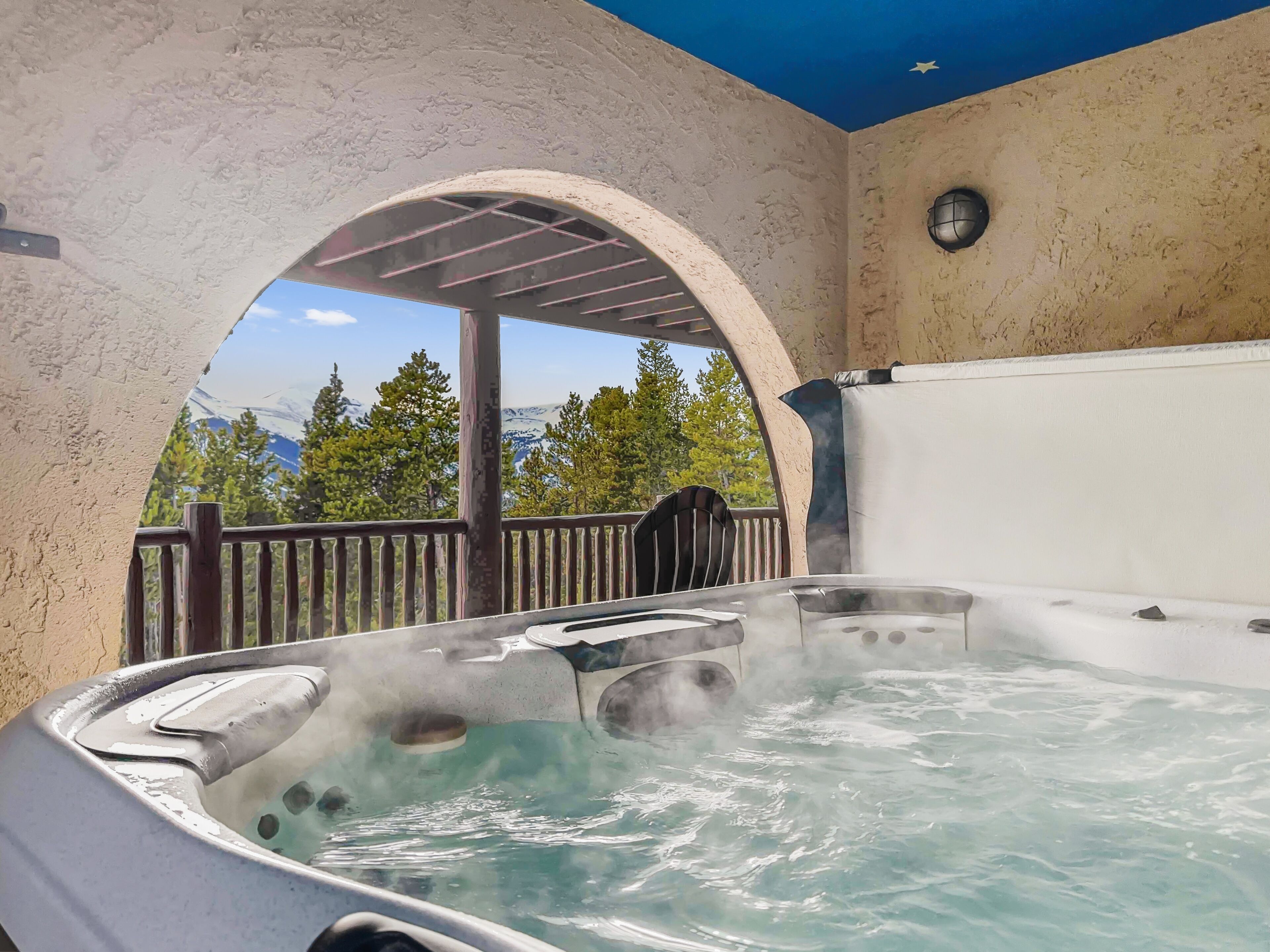 Ein Whirlpool mit aufsteigendem Dampf, umgeben von einer Steinmauer und einem Holzboden.