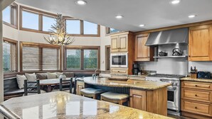 A spacious kitchen with a large island, wooden cabinets, and a built-in stove. - Above the Fray (Breckenridge)