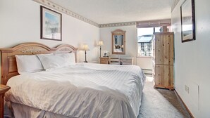 Ein Hotelzimmer mit einem großen Bett, einem Schminktisch, einem Spiegel und einem Kleiderschrank.