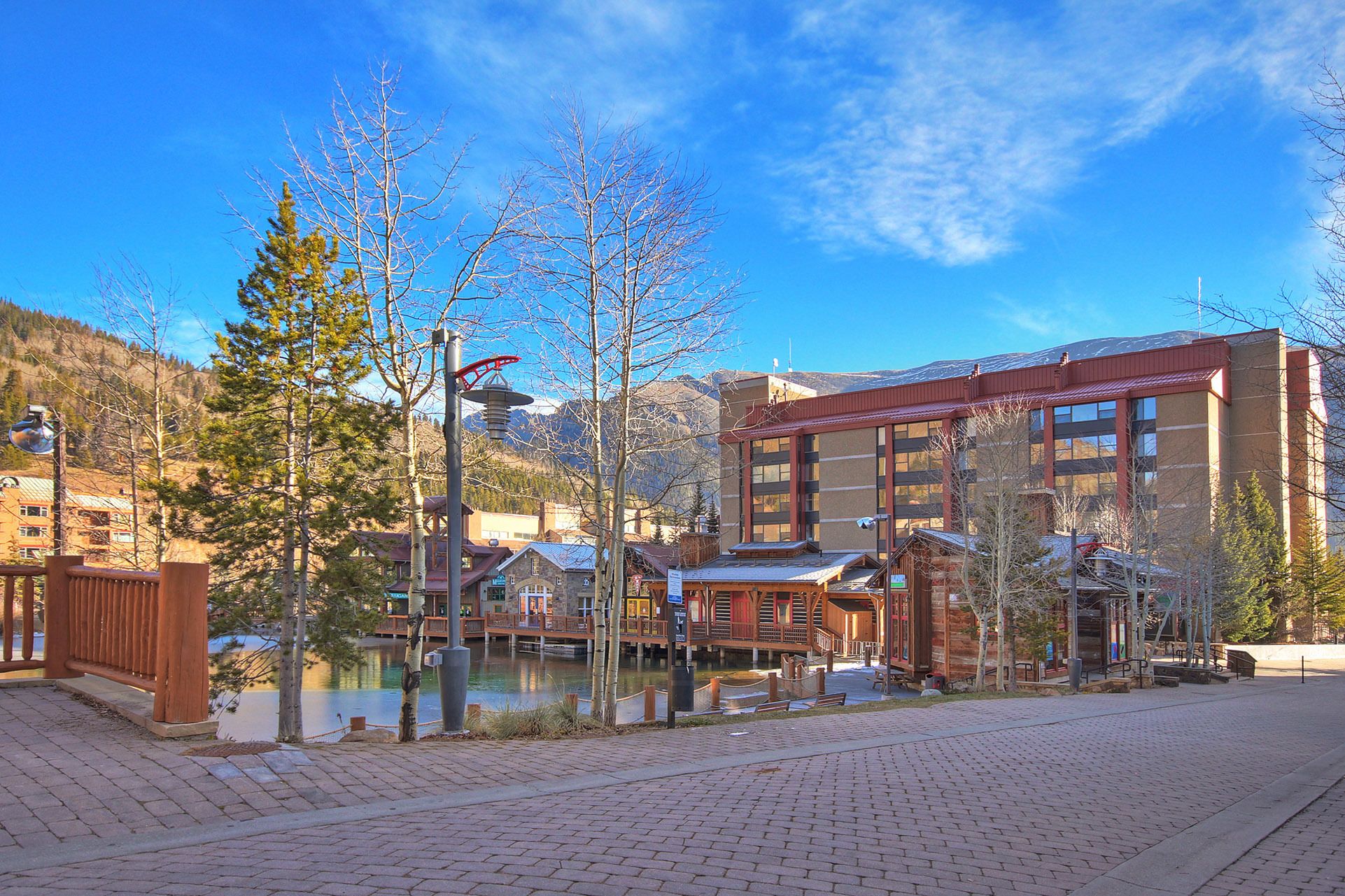 A hotel with a wooden exterior, a dock, and a view of mountains.