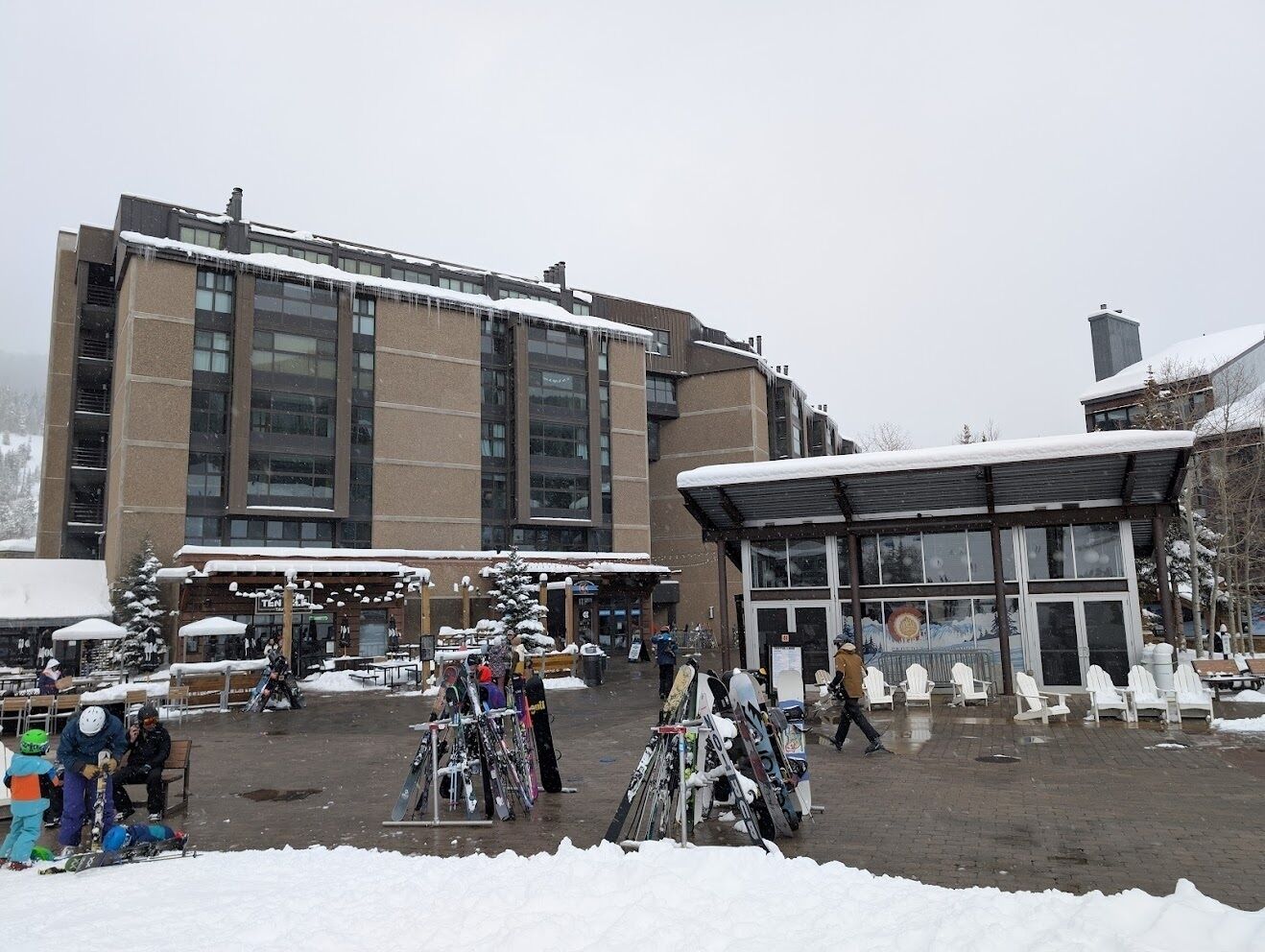 Un edificio con fachada de vidrio amplia y un espacio exterior cubierto con nieve.