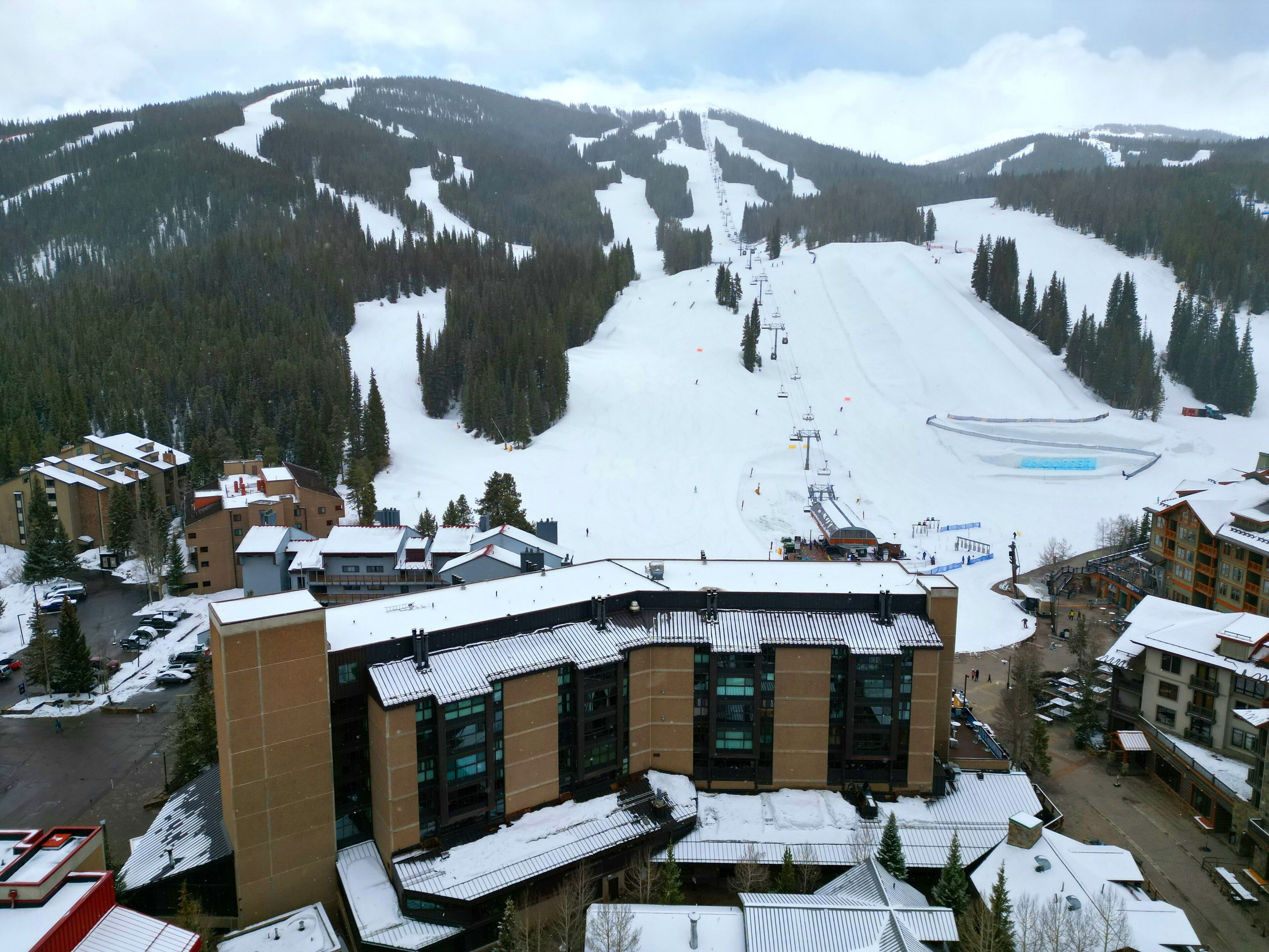 A ski resort with a large ski slope, buildings with multiple floors, and a parking area.