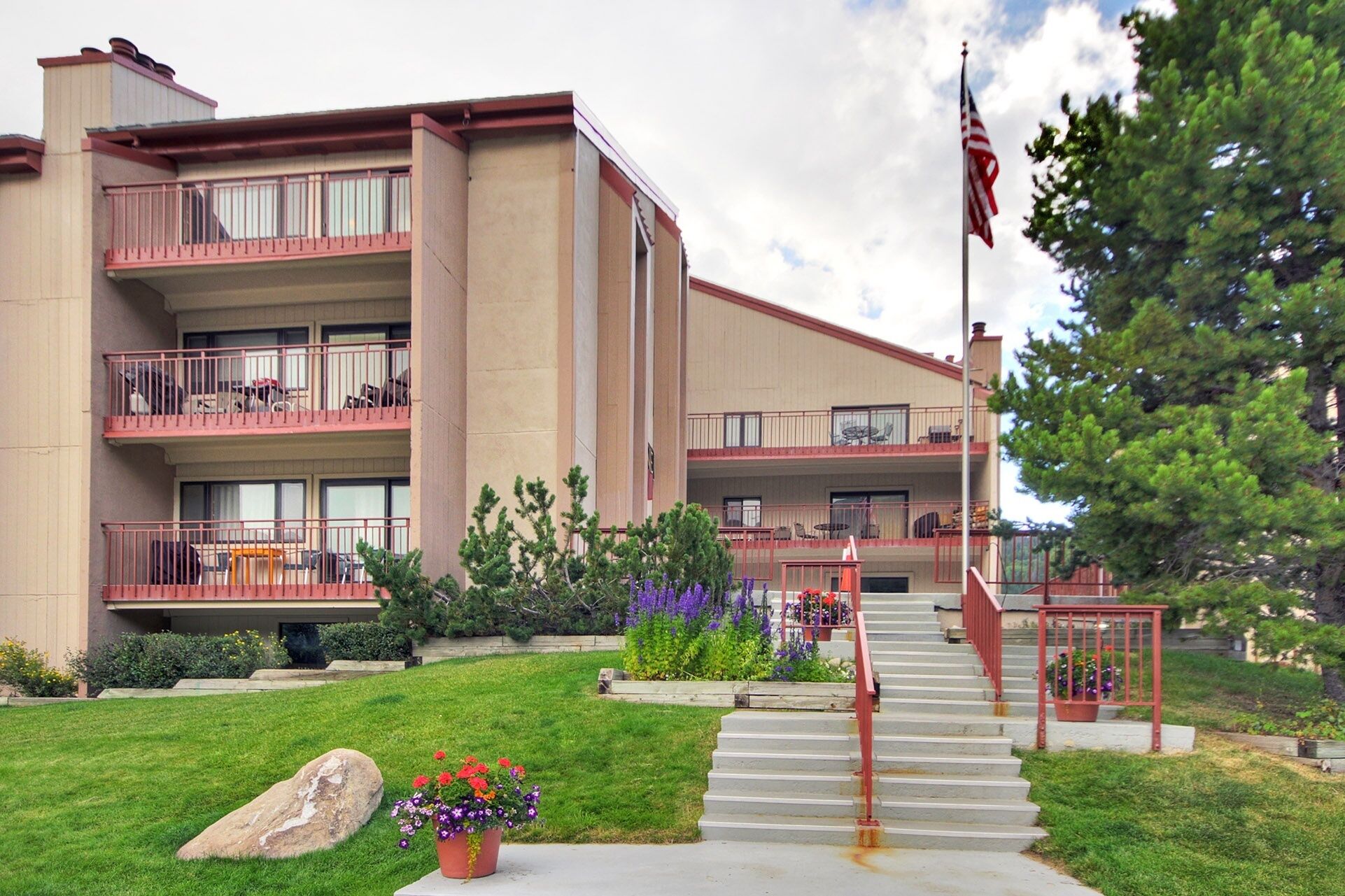A multi-story hotel with balconies, a flagpole, and a well-maintained lawn.