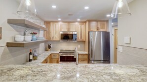A modern kitchen with wooden cabinets, a stainless steel refrigerator, and a marble countertop. - Peregrine Lodge-Remodeled Kitchen-Steps to Super Bee Lift - PG309 by RedAwning (Copper Mountain)