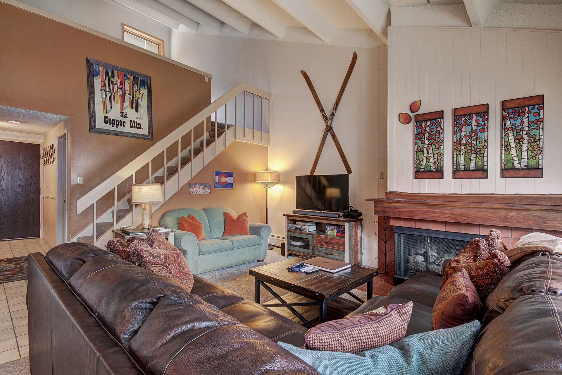 Un salon chaleureux avec une cheminée, un téléviseur et un escalier.