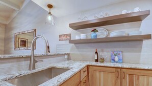 A kitchen with a granite countertop, wooden cabinets, a stainless steel sink, and a hanging light fixture. - Peregrine Lodge-Remodeled Kitchen-Steps to Super Bee Lift - PG309 by RedAwning (Copper Mountain)