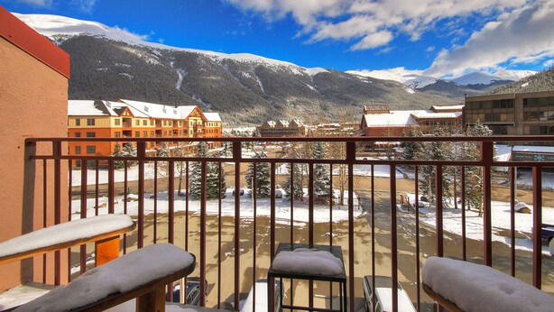 A balcony with a view of snow-covered mountains and buildings. - Peregrine Lodge-Remodeled Kitchen-Steps to Super Bee Lift - PG309 by RedAwning (Copper Mountain)