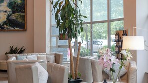 Un salón moderno con sofás color beige, un ventanal grande y una planta en maceta.