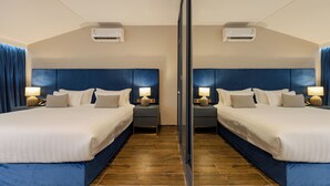 Habitación con espejo, dos camas, mesitas de noche, lámparas y unidades de aire acondicionado.