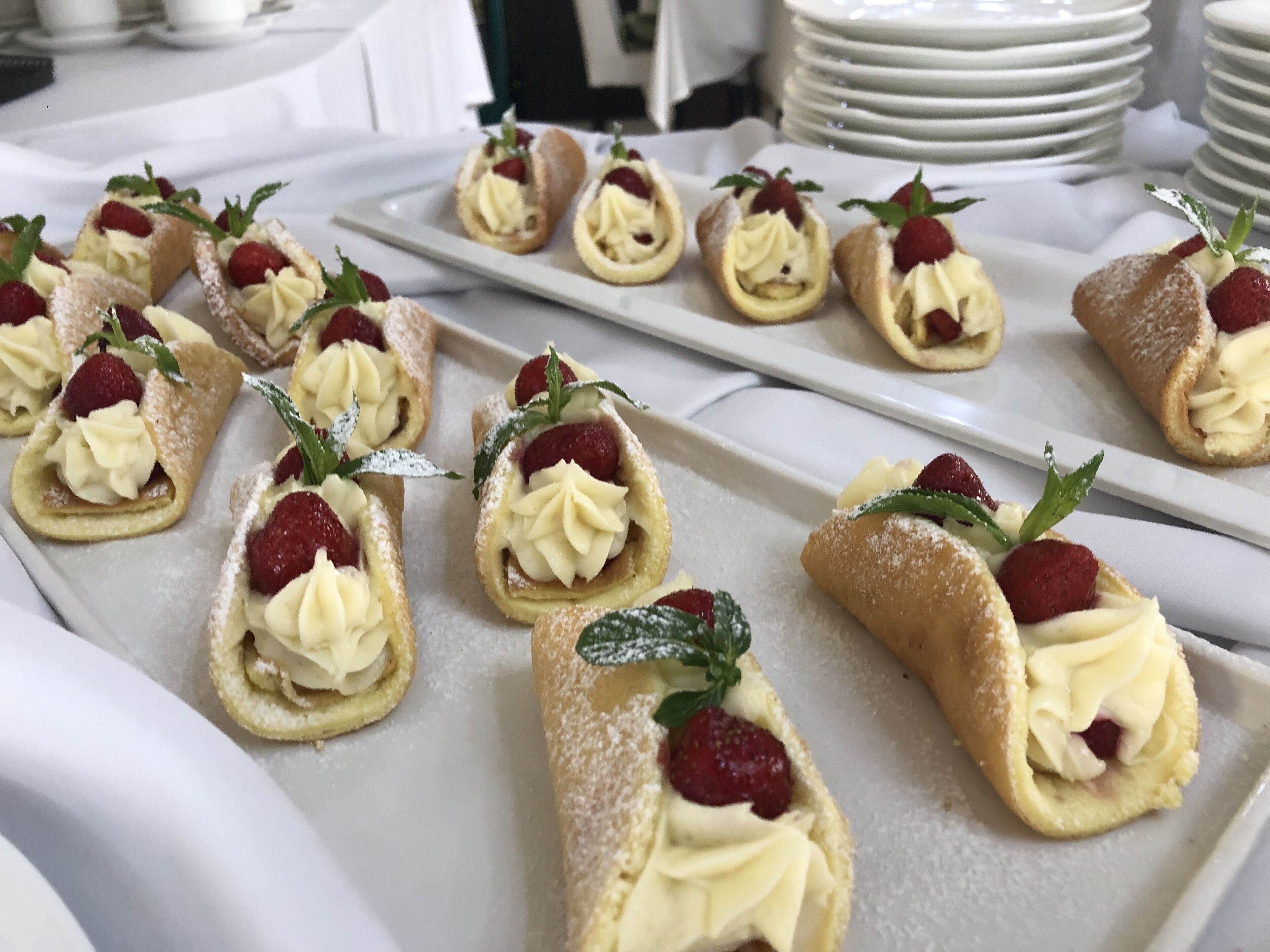 A tray of dessert pastries with cream and strawberries.